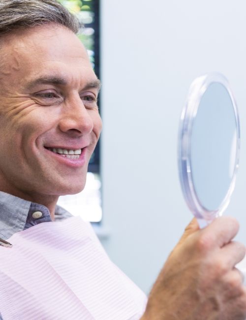 Man looking at smile after one visit dental restoration