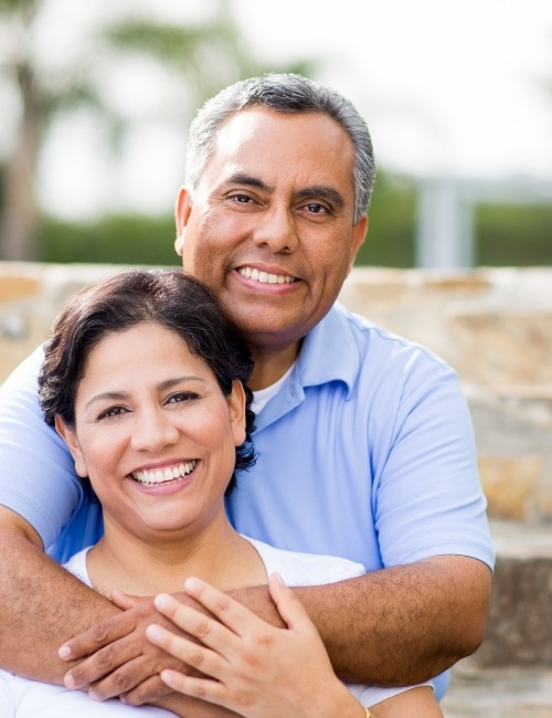 Smiling man and woman enjoying the benefits to dental implants