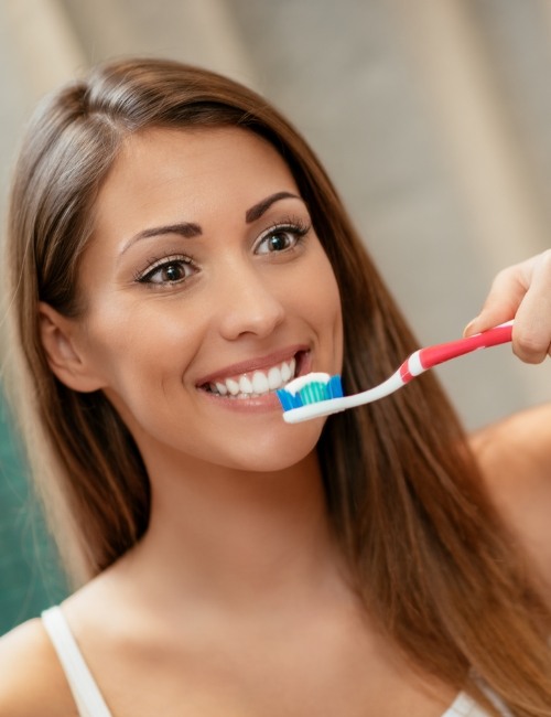 Woman brushing teeth to prevent dental health concerns