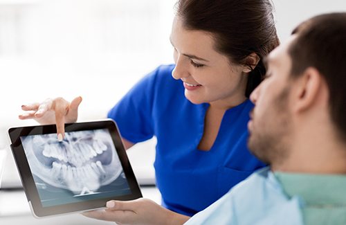Patient and dental assistant looking at X-ray on tablet