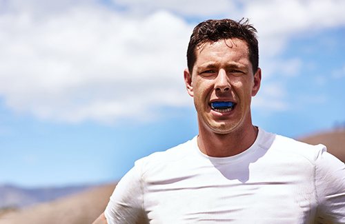 Man wearing blue mouthguard while hiking