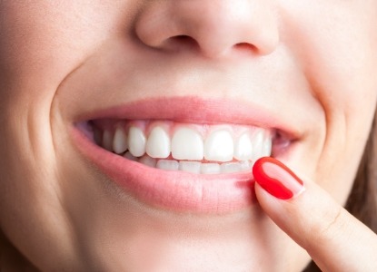 Person pointing to healthy smile after gum disease treatment
