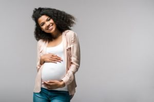 a pregnant woman smiling and holding her belly