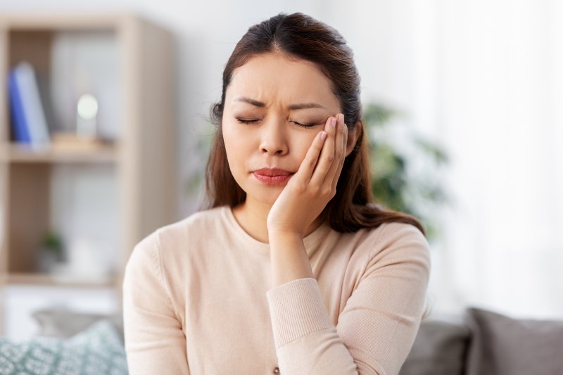 patient suffering from facial pain holding cheek